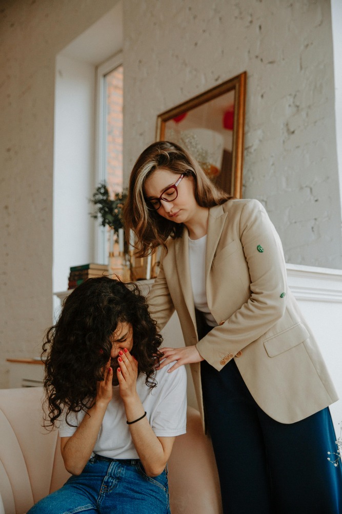 A woman in formal attire is seen consoling a crying girl