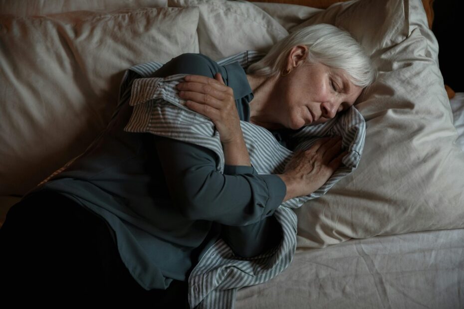 An old woman in bed sleeping is seen hugging a shirt